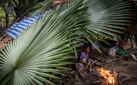 Un niño Maniq se calienta junto al fuego en su cabaña en Phatthalung, en el sur de Tailandia.