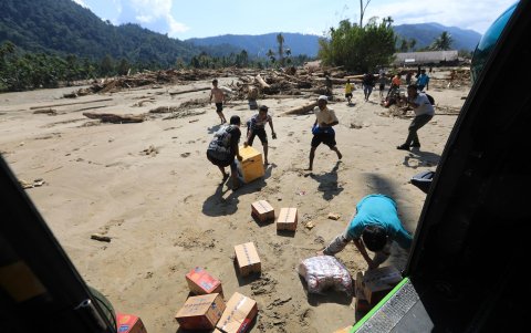 Los residentes reciben ayuda alimentaria entregada en helicóptero cortesía de las tropas de las Fuerzas Armadas Nacionales de Indonesia.