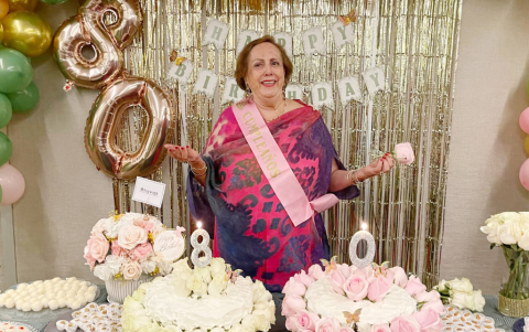 La cumpleañera junto a la mesa de dulces.