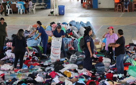 Personas clasifican objetos de ayuda humanitaria en un coliseo habilitado como albergue este domingo 14 de diciembre, en El Torno (Bolivia).