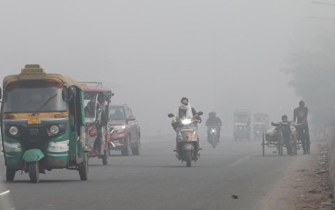 Vehículos transitan por calles en Nueva Delhi con poca visibilidad debido a la contaminación del aire en India.