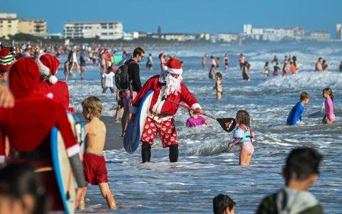 Surfistas y espectadores, algunos vestidos de Papá Noel, participan en el 17º evento anual 