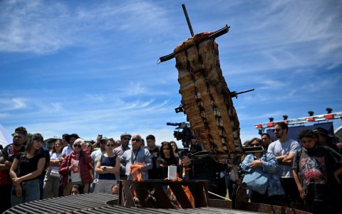 La gente se encuentra junto a la carne asándose en una barbacoa durante el festival 