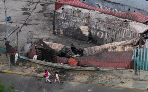 Peatones caminan cerca de contenedores destruidos en el puerto de La Guaira, Venezuela.