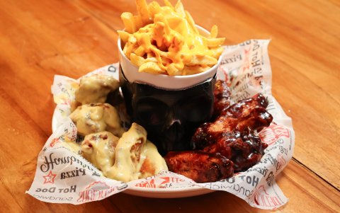 Uno de los platos destacados son las alitas de distintos sabores servidas junto a un caldero de bruja lleno de papas fritas.