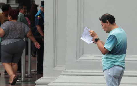 Contribuyentes revisando los comprobantes de pago para entender qué tipo de valores les cobraron, es una escena recurrente en estos días, afuera del Municipio de Guayaquil.