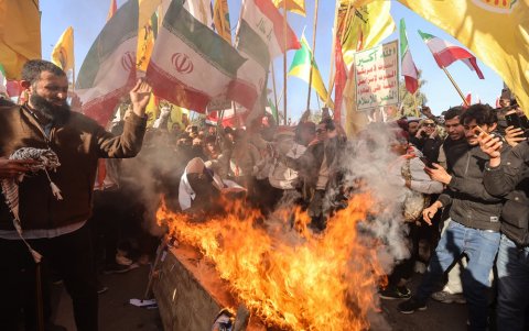 Manifestantes queman banderas estadounidenses e israelíes durante una manifestación cerca de la embajada iraní en Bagdad el 16 de enero de 2026.