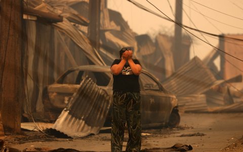 Un residente reacciona frente a los restos carbonizados de casas destruidas y un vehículo después de un incendio forestal en Concepción, Chile, el 18 de enero de 2026.