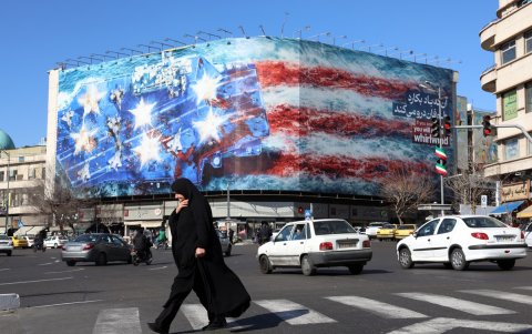 Una mujer iraní con velo camina cerca de un enorme cartel antiestadounidense colgado en la plaza Enqelab en Teherán, el sábado 31 de enero de 2026.