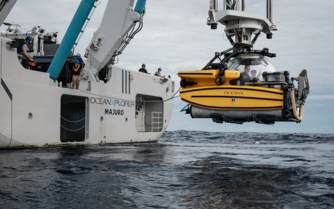 Un sumergible siendo bajado por una grúa desde el OceanXplorer, un buque de investigación operado por la organización marina sin fines de lucro OceanX.