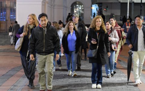 Participantes del Paseo Express avanzando a pie por calles empedradas del Centro Histórico de Quito, en un ambiente nocturno seguro y animado.