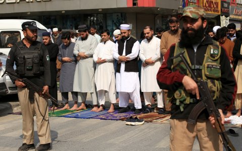 Oficiales de seguridad y musulmanes civiles en una calle de Peshawar, en Pakistán.