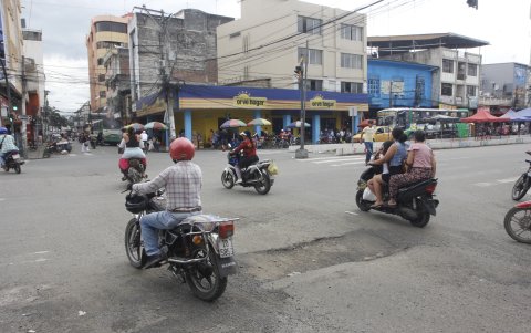 Motociclistas sin casco circulan por las calles de Milagro, donde los huecos ponen en riesgo la estabilidad de estos vehículos motorizados.