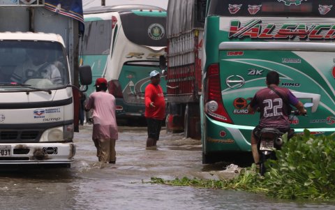 En la vía Babahoyo–Jujan, algunas personas se ofrecen como guías para ayudar a los conductores a esquivar huecos en medio de la inundación.