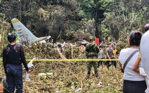 Varias personas y soldados se encuentran junto a los restos de un avión Hércules de la Fuerza Aérea que se estrelló durante el despegue, en Puerto Leguizamo (Colombia), el 23 de marzo de 2026.