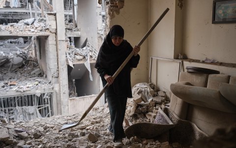 Una mujer trata de limpiar una vivienda en el barrio de Haft Chenar de Teherán que resultó dañada en un ataque de Estados Unidos e Israel.