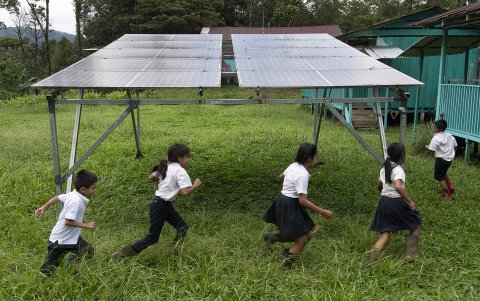 Los niños juegan alrededor de paneles solares de la escuela comunitaria Nairi Awari en Limón, Costa Rica.