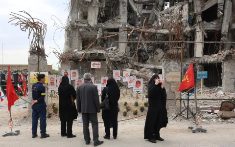 Varias personas se reúnen para observar fotografías de los fallecidos en un ataque aéreo estadounidense-israelí contra un edificio residencial en Teherán, Irán, el 13 de abril de 2026.