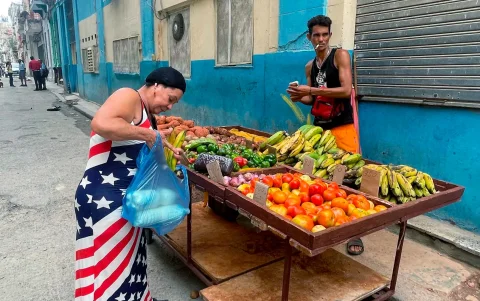 Una mujer vestida con los colores de la bandera de Estados Unidos compra frutas a un vendedor ambulante este viernes, en una calle de La Habana (Cuba).