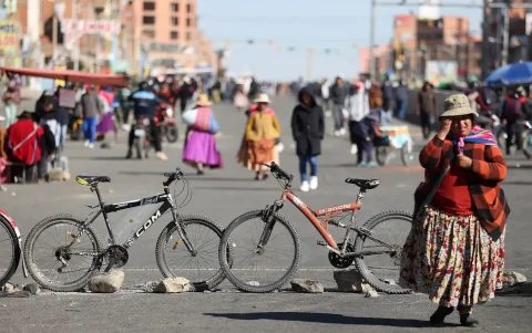 Una mujer camina durante manifestaciones de campesinos de los 'Ponchos Rojos' que exigen la renuncia del presidente boliviano, Rodrigo Paz, en El Alto (Bolivia).