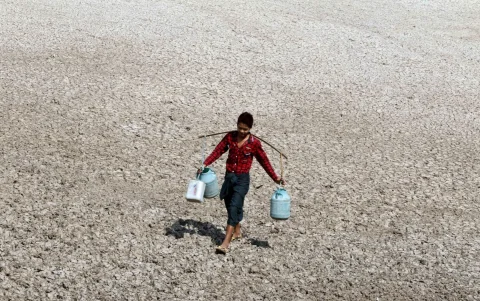 Un niño acarrea unos bidones con agua en plena sequía a causa de El Niño en Mandalay, Birmania.