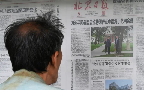 Un hombre lee un periódico en Pekín sobre la visita de Donald Trump a Xi Jinping.