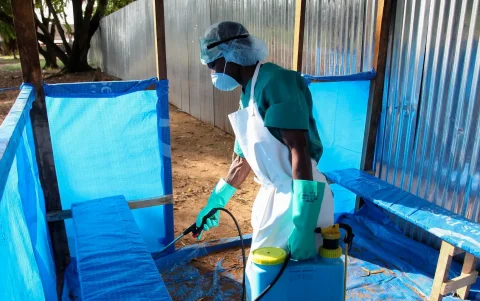 Una enfermera liberiana rocía desinfectante como medida de prevención contra el mortal virus del ébola en la sala de espera exterior en Monrovia, Liberia.