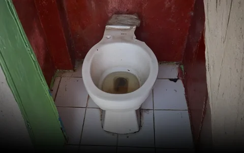 Baños deteriorados, con aguas acumuladas y filtraciones, afectan a estudiantes de la escuela fiscal en Puente Lucía.