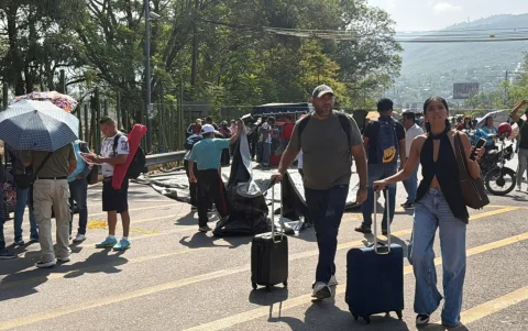 Pasajeros caminan durante manifestación de la Coordinadora Nacional de Trabajadores de la Educación (CNTE) este martes, frente al Aeropuerto Internacional de la ciudad de Oaxaca (México).