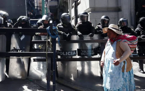 Una mujer aimara camina frente a un grupo de policías durante una protesta por quinta semana consecutiva este 1 de junio de 2026, en La Paz (Bolivia).