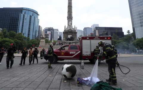 Integrantes del Cuerpo de Bomberos apagan un balón incendiado este martes, durante una manifestación en Ciudad de México (México).