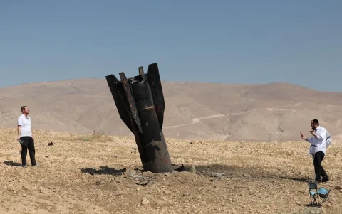 Judíos ultraortodoxos miran los restos de un misil balístico iraní que aterrizó en un campo abierto junto al asentamiento de Mevo'ot Yericho en Cisjordania, en el Valle del Jordán, este lunes.