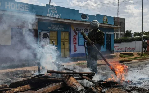 Agentes de la policía keniana despejan una hoguera utilizada por manifestantes para bloquear una carretera durante una protesta en Nanyuki, Kenia, el 9 de junio de 2026.