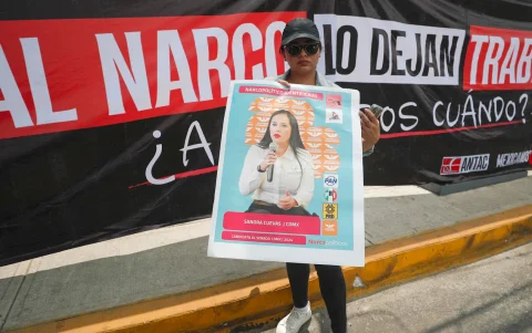 Un manifestante muestra un cartel con mensajes contra la narcopolítica durante la protesta realizada este jueves en las inmediaciones del estadio de Ciudad de México.
