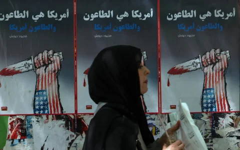 Una mujer pasa junto a carteles políticos colgados en la pared en una calle de Beirut, Líbano, 09 de junio de 2026.