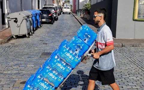 Un hombre transporta botellas de agua tras la interrupción del servicio este lunes, en San Juan (Puerto Rico).