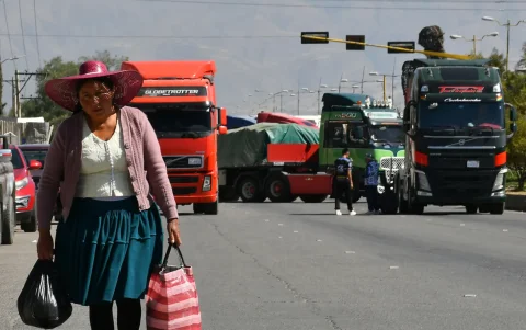 Una mujer quechua camina frente a vehículos de una caravana de transportistas para exigir el levante de los bloqueos de carreteras este lunes, en Cochabamba (Bolivia).