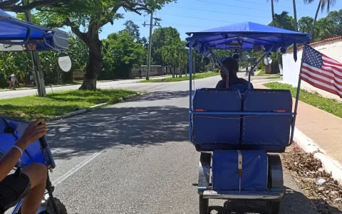 Un bicitaxi circula por una avenida con una bandera de Estados Unidos en La Habana (Cuba).