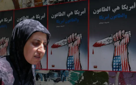 Una mujer pasa junto a carteles políticos colgados en la pared de una calle de Beirut, Líbano.
