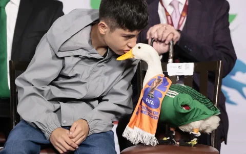 Carlos besa al pato Merlín, vestido con una camiseta de la Selección Mexicana de Fútbol, durante una visita a la presidenta de México