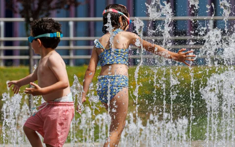 Varios niños disfrutan en unas fuentes en Zaragoza, este domingo.