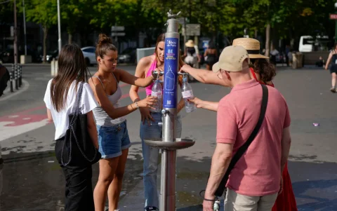 Grupos de personas se hidratan en una fuente este martes 23 de junio de 2026 en París.