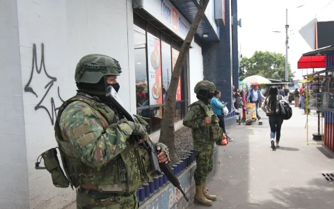 Dos militares resguardan una zona de afluencia de civiles en una ciudad.