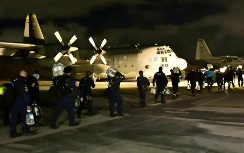 Fotografía cedida por la UNGRD que muestra a integrantes del grupo de búsqueda y rescate USAR COL-1 durante una operación logística nocturna en un avión militar.