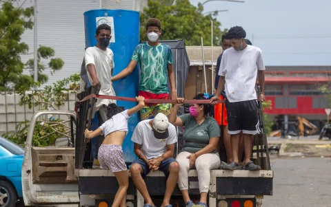 Personas suben a un vehículo en una zona donde colapsaron edificios tras los terremotos que asolaron a Venezuela en La Guaira.