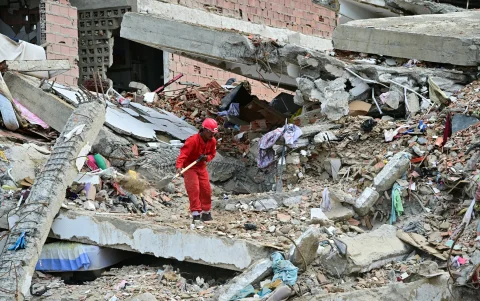 Un trabajador remueve escombros de un edificio colapsado en La Guaira.