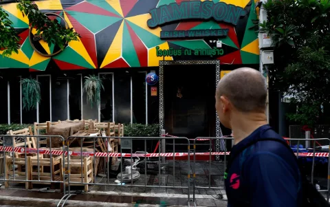 Un peatón pasa junto a un pub que fue escenario de un incendio fatal en Bangkok.
