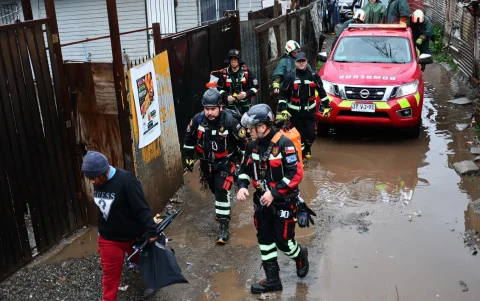 Un grupo de bomberos llega a evacuar un campamento que presenta riesgo de inundación.