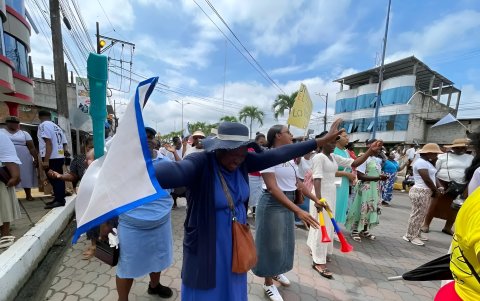 Una mujer eleva sus brazos en señal de oración durante la caminata por la paz en San Lorenzo, norte de Esmeraldas.