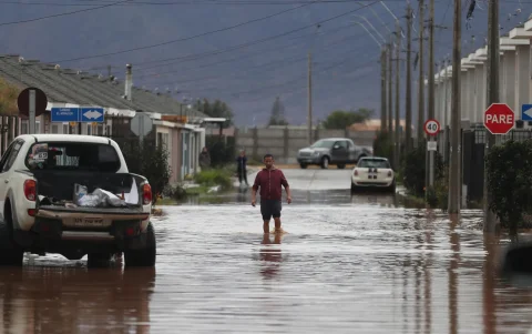 Una persona camina por una calle inundada en el barrio Mirador de Hacienda, en La Serena (Chile).